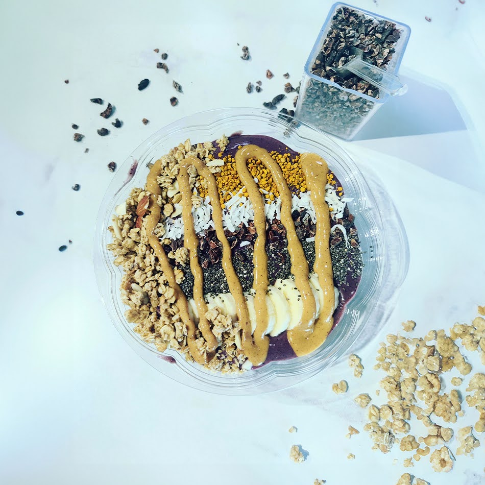 A nutritious and delicious bowl made with acai berries, bananas, and granola, topped with cacao nibs, chia seeds, and bee pollen.